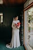 bride holding her bright pink floral while looking at the window- Waikanae Wedding