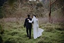 bride and groom holding each other as they walk in the middle of the forest- Waikanae Wedding