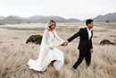 bride and groom holding each other as they walk pass the cold breeze- New Zealand Elopements