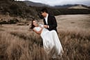 bride and groom having their couple dance in the middle of grassy mountains- New Zealand Elopements